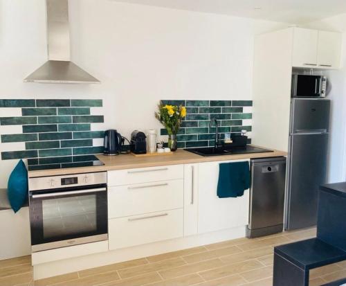 une cuisine avec des placards blancs et du carrelage bleu sur le mur. dans l'établissement EDEN LES PINS, à Antibes