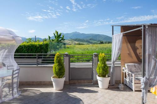a balcony with two potted plants and a view of a field at Bed & Breakfast Cozy Hills in Cagli