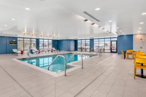 a pool in a building with tables and chairs at Home2 Suites By Hilton Bozeman Four Corners in Bozeman