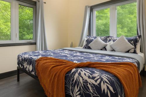 a bed in a bedroom with two windows at The Grassy Oasis in Brampton