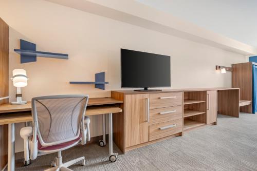 a room with a desk with a tv and a chair at Home2 Suites By Hilton Bozeman Four Corners in Bozeman