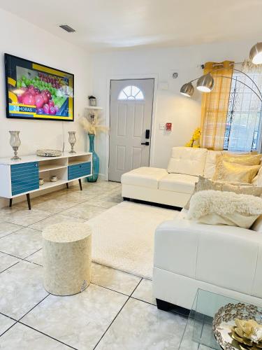 a living room with two white couches and a tv at Miami Casa in Miami Gardens