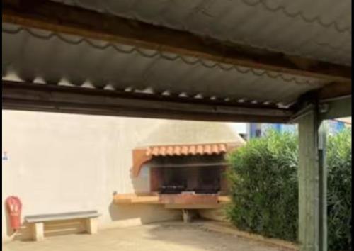 un four à pizza sur le côté d'un bâtiment avec un banc dans l'établissement Résidence primavera cap d agde, au Cap d'Agde