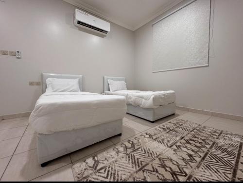 a bedroom with two beds and a fan and a rug at غرفتين نوم وصالة بدخول ذكي in Al Rass