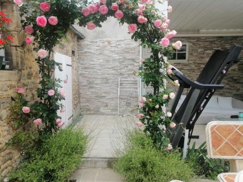 Un arco floral con rosas rosadas y una silla negra. en D-DAY's, en Bayeux