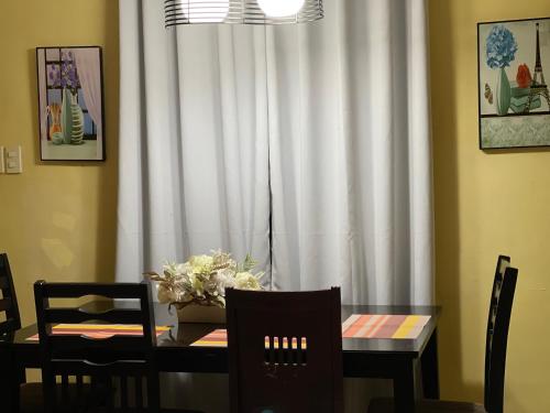 a dining room table with a white curtain and a table with chairs at SHANA Transient House San Jose De Monte with 3 bedrooms in Muzon
