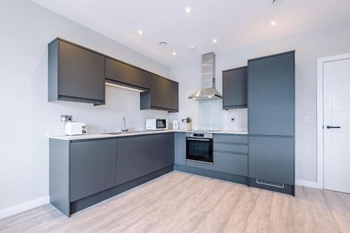 a large kitchen with gray cabinets and appliances at Elysée Suites - Lovely 2 Bed Flat in Southport in Southport