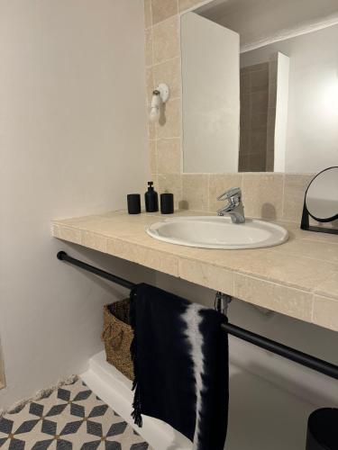 un lavabo de salle de bain avec une serviette noire suspendue en dessous dans l'établissement Mas d'Oleandre, à Montaren-et-Saint-Médiers