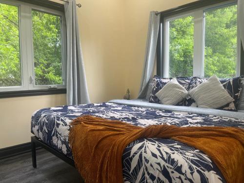 a bed in a bedroom with two windows at The Grassy Oasis in Brampton