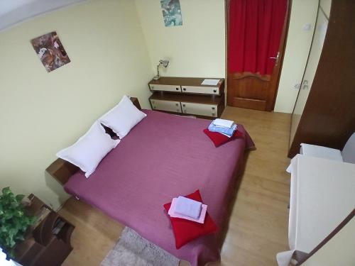 a small bedroom with a purple bed with red pillows at sobe MAŠA in Subotica