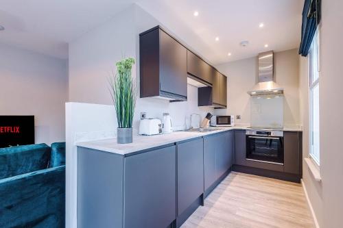 a kitchen with blue cabinets and a blue couch at Elysée Suites - Modern 1 Bed Flat in Southport in Southport