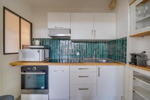 une cuisine avec des armoires blanches, un évier et un micro-ondes dans l'établissement Appartement très charmant à Bordeaux, à Bordeaux