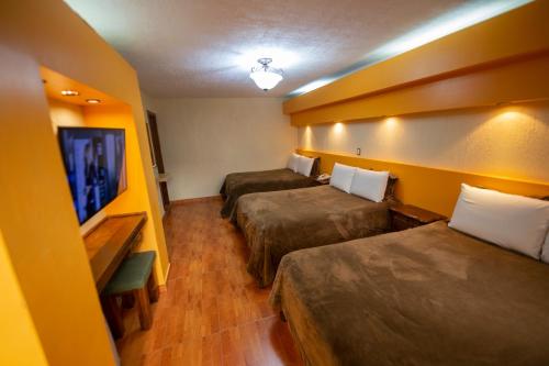 a hotel room with two beds and a flat screen tv at Gran Hotel El Encanto in San Cristóbal de Las Casas