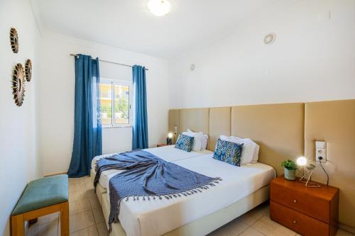 a bedroom with a large bed with blue curtains at Pool&Beach in Encosta de São José in Albufeira