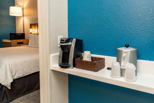 a room with a bed and a shelf with a coffee maker at Holiday Inn Express Hotel & Suites Orange City - Deltona by IHG in Orange City