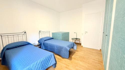 two beds in a bedroom with blue sheets at S354 - Sirolo, comodo quadrilocale a 100mt dal centro in Sirolo