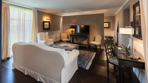 a living room with a white couch and a television at Relais Villa D'Amelia in Benevello