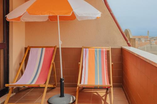 two chairs sitting under an umbrella on a balcony at Torreira Beach Apartment in Torreira
