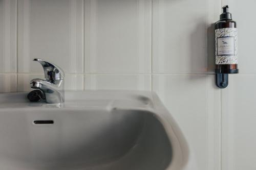 a white sink in a bathroom with a bottle on the wall at Torreira Beach Apartment in Torreira