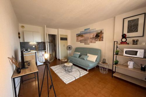 un salon avec un canapé bleu et une cuisine dans l'établissement Studio with pool close to the beach, à Fréjus
