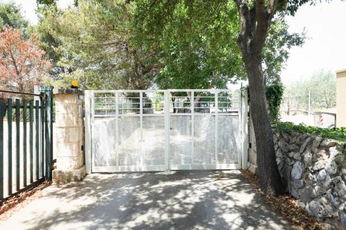 a gate with a tree next to a stone wall at GuestHost - Trulli La Ghianda in Noci