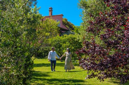 Un hombre y una mujer caminando entre los árboles en Agriturismo Bio Podere Doganelle, en Giuncarico