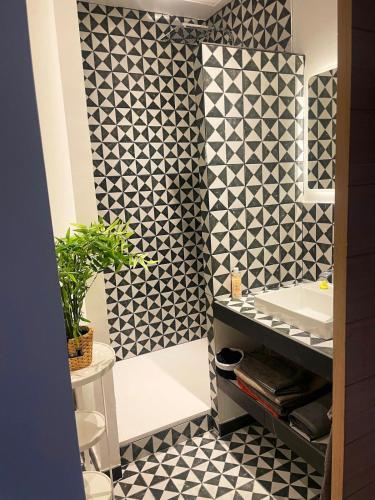 La salle de bains est pourvue de carrelage noir et blanc et d'un lavabo. dans l'établissement Maison 217, à La Celle-sous-Gouzon