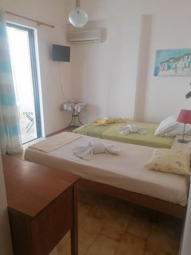 two beds in a room with a window at Love Greece Dream Pavlaras in Tolo