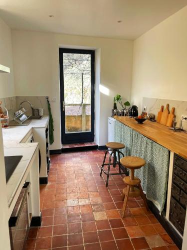 - une cuisine avec un comptoir et deux tabourets dans l'établissement Maison 217, à La Celle-sous-Gouzon