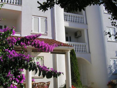 un bâtiment avec des fleurs violettes devant lui dans l'établissement Apartments Paloma Blanca, à Medulin