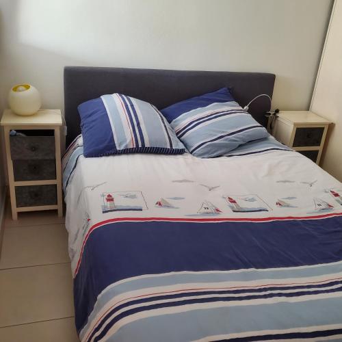 - un lit avec des couvertures et des oreillers bleus et blancs dans l'établissement appartement rdc jardin, au Grau-du-Roi