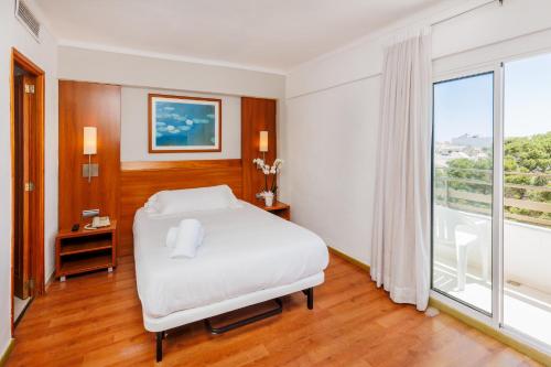 a bedroom with a white bed and a large window at O7 Colombo in S'Illot