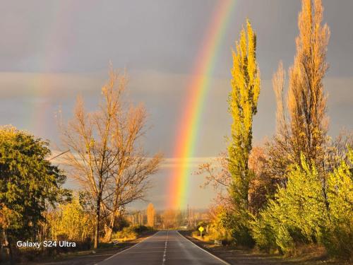 a rainbow in the sky over a road at Espacio Nux in Los Árboles