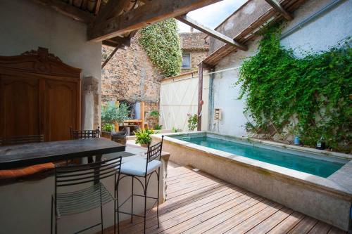 une terrasse avec une piscine, une table et des chaises dans l'établissement Old wine storehouse and its outbuilding, à Gabian