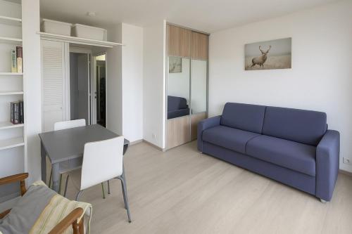 un salon avec un canapé bleu et une table dans l'établissement Luminous apartment with sea view in La Ciotat, à La Ciotat