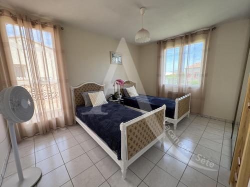 - une chambre avec 2 lits, un ventilateur et des fenêtres dans l'établissement Maison 6 personnes, salon climatise, wifi et stationnement, à Sète