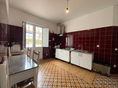 a kitchen with red tiled walls and a table at Hostel Rossio Alcobaça in Alcobaça
