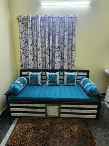 a bed in a room with blue pillows and a curtain at Sri Sakthi Home Stay - Beyond the Expectations - We maintain standards in Tirupati