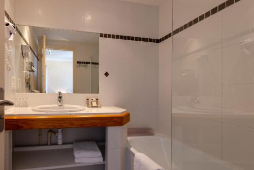 a bathroom with a sink and a tub and a shower at Family Golf Hotel in Royan