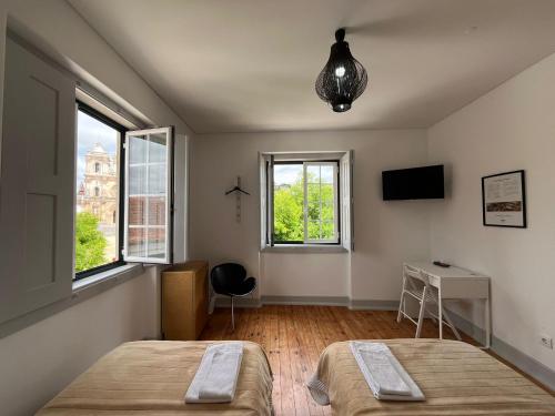 two beds in a room with two windows at Hostel Rossio Alcobaça in Alcobaça