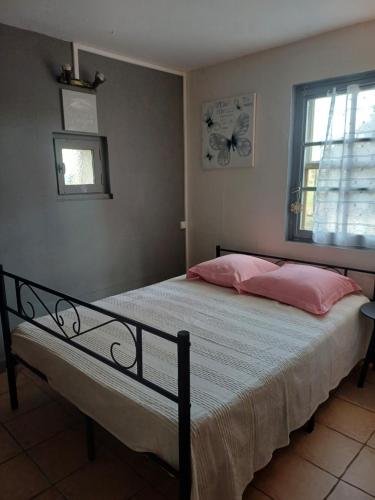 - une chambre avec un lit doté d'oreillers roses et d'une fenêtre dans l'établissement petite maison dans la campagne a 10 mn a pied du centre ville, à Arles