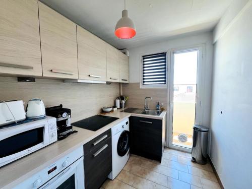 une cuisine avec un évier et un micro-ondes dans l'établissement Le barquier, à Antibes