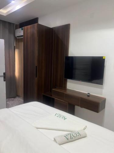 a bedroom with a bed and a entertainment center with a tv at Koza Park Apartment in Benin City
