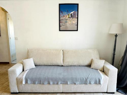 - un canapé blanc dans le salon avec une photo sur le mur dans l'établissement Le barquier, à Antibes