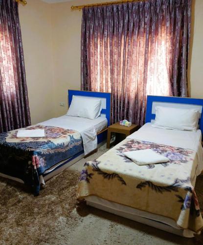 um quarto com duas camas e cortinas com toalhas em Petra Triclinium Home em Wadi Musa