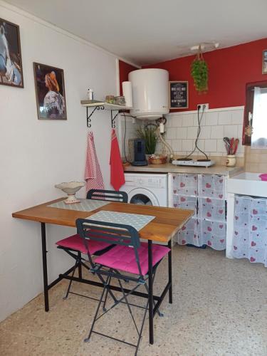 une cuisine avec une table en bois et des chaises roses dans l'établissement petite maison dans la campagne a 10 mn a pied du centre ville, à Arles