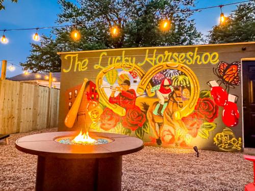 a fire pit in front of a wall with a mural at The Lucky Horseshoe 4BR Derby Side Retreat in Louisville