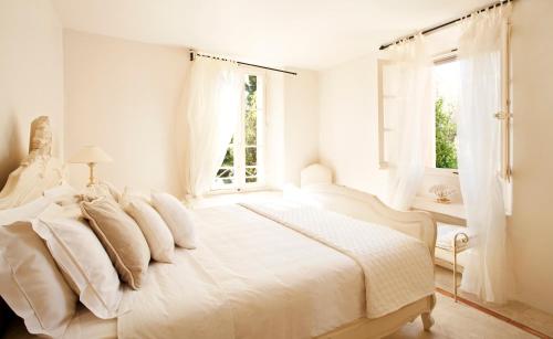 a white bedroom with a white bed and a window at Maison Jolie in Saint-Tropez