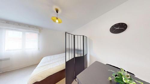 une chambre avec un lit et une horloge au mur dans l'établissement Studio - Jean-Jacques Rousseau, au Havre