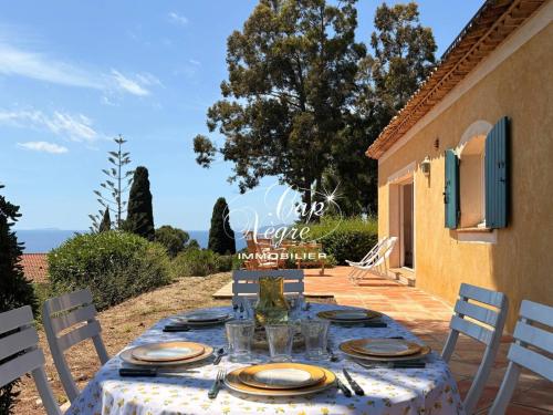 a table with plates and glasses on a patio at maison pour 9 personnes vue mer a 150 m de la plage du rayol in Rayol-Canadel-sur-Mer